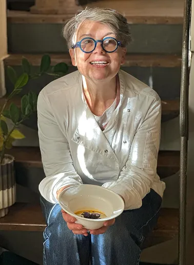 Cristina, la chef del ristorante con in mano un piatto con crema con zucca, fonduta e riso, preparato nel ristorante da Alcide a Venturina, in Toscana.