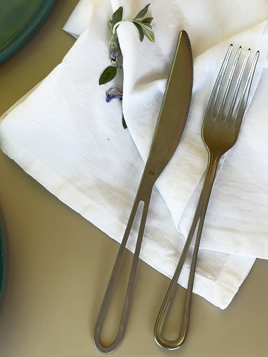 Dettaglio tavola apparecchiata con un tovagliolo in cotone bianco e posate eleganti in metallo