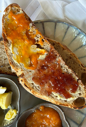 Slice of homemade bread with butter and jam.