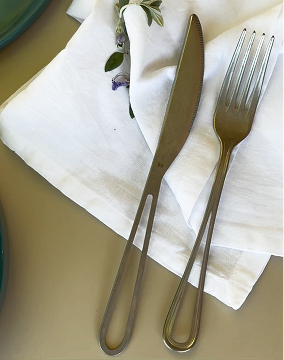 Detail of a table set with a white cotton napkin and elegant metal cutlery