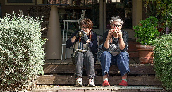 Le sorelle, Francesca e Cristina, mentre addentano due panini a sedere sugli scalini della pedana in legno fuori dal ristorante da Alcide.