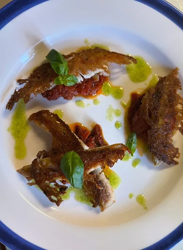 Dettaglio piatto di mare con acciughe, burrata e basilico