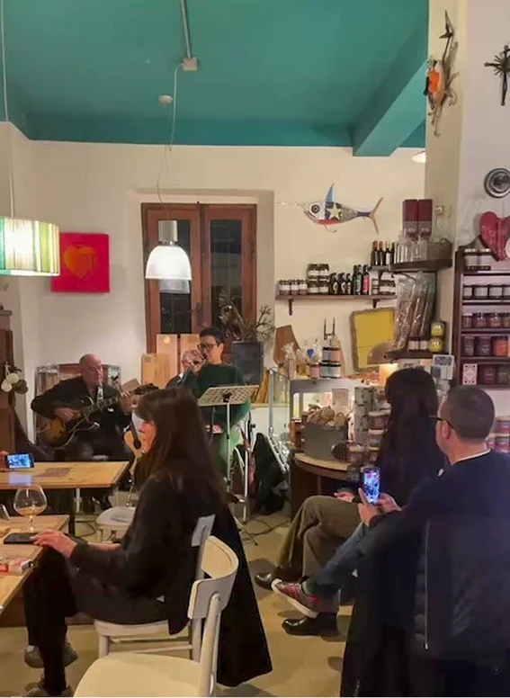 Interno del ristorante con persone a sedere e musica dal vivo.